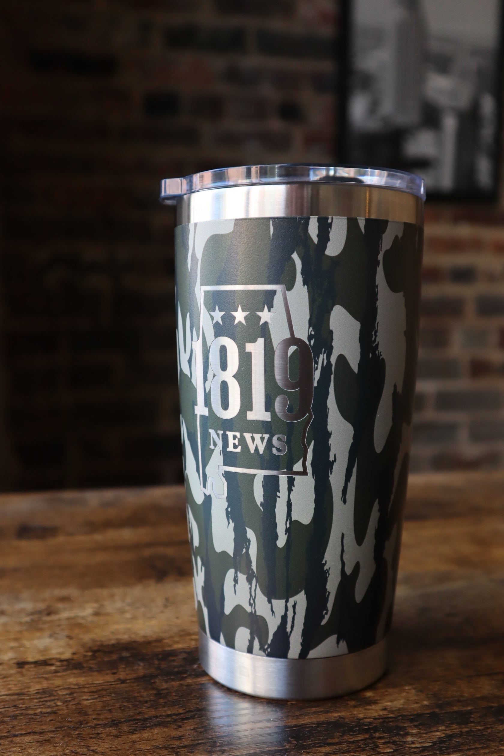 Metallic cylindrical object with camouflage pattern and '1819 NEWS' branding.